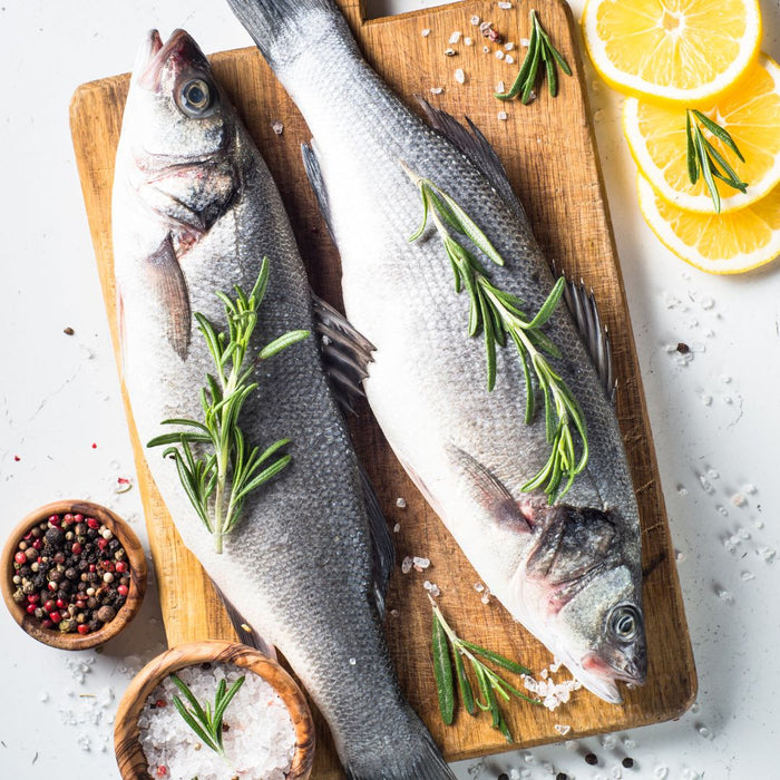 Two Fresh Seabass On A Wooden Plate